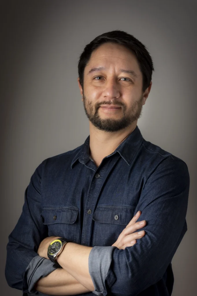 Francisco Masuda, de braços cruzados, sorrindo levemente