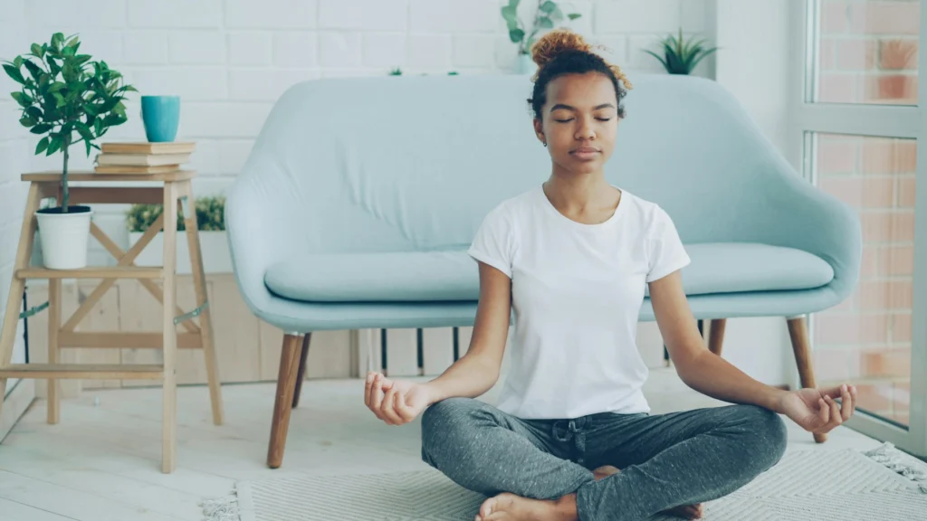 Jovem meditando sentada no chão da sala